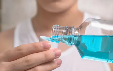 Niebieski płyn do płukania jamy ustnej, z butelki przelewany do nakrętki. Idealny do odświeżenia oddechu.