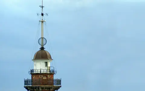 Szczyt latarni morskiej w Gdańsku z wiatrowskazem i kulistą ozdobą.