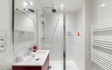 Salle de bain moderne, prête pour la prochaine étape de rénovation. Douche, lavabo et sèche-serviettes blancs.