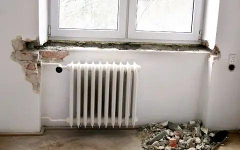 Rozpoczęła się wymiana parapetu wewnętrznego. Widać gruz pod oknem i odsłoniętą cegłę.