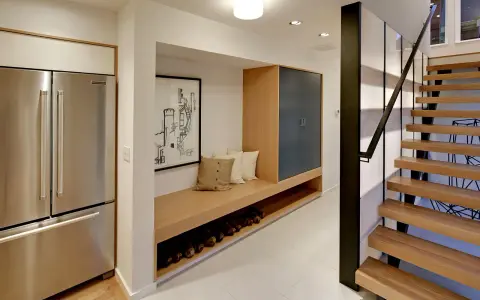 Ideas para decorar un pasillo interior: un banco de madera con almacenamiento, cuadros y una escalera moderna.