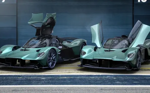 Zwei Aston Martin Valkyrie Spider in Mintgrün mit geöffneten Flügeltüren stehen nebeneinander.