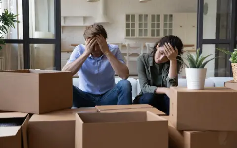 Couple overwhelmed by the stress of moving, surrounded by moving boxes.