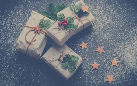 Julklappar inslagna i brunt papper med granris och stjärnor. Perfekta julkort idéer för en mysig julkänsla.