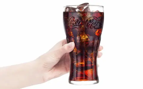 Hand hält Glas mit eiskalter Cola. Frage: Ist Cola in der Schwangerschaft erlaubt?