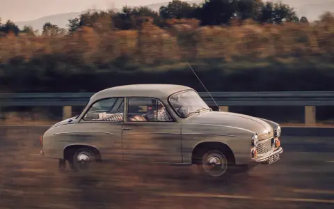 Klasyczny Syrena 105 na drodze, uchwycony w dynamicznym ujęciu panning shot.