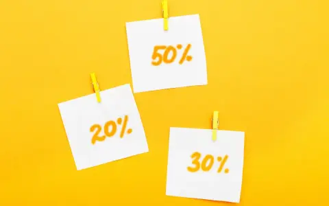 Trzy karteczki z napisami 20%, 30% i 50% przyczepione żółtymi spinaczami. Idealne zniżki dla emerytów!