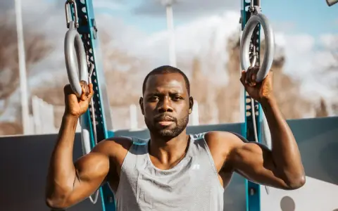 Un homme musclé s'entraîne avec des anneaux de street workout maison.