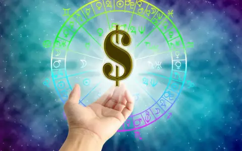 Znak dolara unosi się nad dłonią na tle koła zodiaku. Czy to zapowiedź sukcesu w pracy dla Ryb?