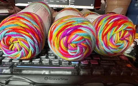 Three balls of brightly colored, variegated yarn sit on a keyboard.