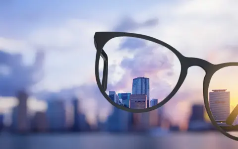 Okulary progresywne z szerokim polem widzenia wyostrzają miejski krajobraz o zachodzie słońca.
