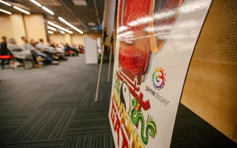 Na konferencji o grach planszowych, z bliska widać planszę z logo "gamedesire" i smoczym motywem.