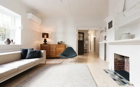 Salon lumineux avec canapé, fauteuil, buffet en bois et cheminée. Idéal pour savoir comment trouver un appartement rapidement.