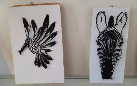 Två spik tavlor med djurmotiv: en kolibri och ett zebrans huvud, skapade med tråd och spik.