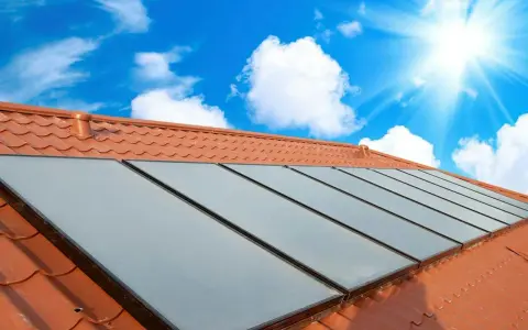 Fakta om solceller: Solpaneler på ett tegeltak fångar solens energi under en klarblå himmel med moln.