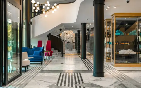 Eleganckie wnętrze bankietowe z niebieską kanapą i czerwonymi fotelami. Przyczyny powrotu do stylistyki art deco w nowoczesnych wnętrzach bankietowych widać w geometrycznych wzorach i luksusowych materiałach.