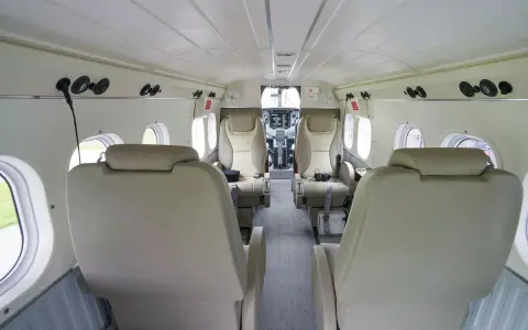 Innenraum einer DHC-6 Twin Otter mit bequemen Ledersitzen und Blick auf das Cockpit.