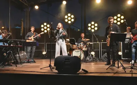 Zespół muzyczny na scenie: wokalistka, gitarzysta, klawiszowiec, saksofonista, basista i perkusista.
