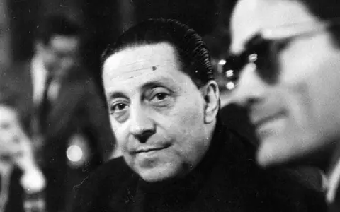 Ritratto in bianco e nero di Sandro Penna, poeta, con uno sguardo intenso. Le sue poesie sono un tesoro della letteratura italiana.
