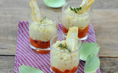 Trois verrines artichaut, garnies d'une purée crémeuse et d'une touche de sauce tomate, sur un fond de bois rustique.