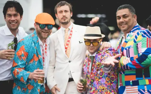 Men at the Kentucky Derby sport vibrant, patterned suits, showcasing bold fashion choices.
