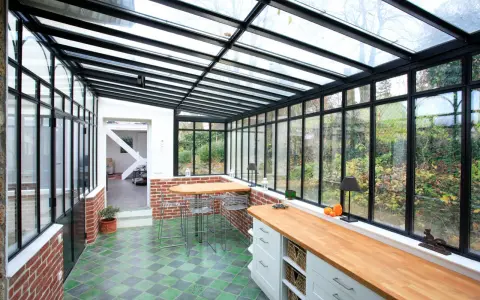 Un'idea per ampliare la cucina nella veranda: un ambiente luminoso con bancone in legno, zona pranzo e vista sul giardino.