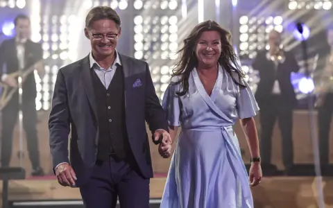 Lotta Engberg och ett leende raffset på scenen, med ett band i bakgrunden.