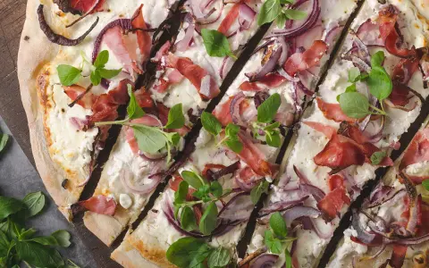 Flammkuchen mit Speck, roten Zwiebeln und frischen Kräutern – tolle Flammkuchen Belag Ideen für jeden Geschmack.