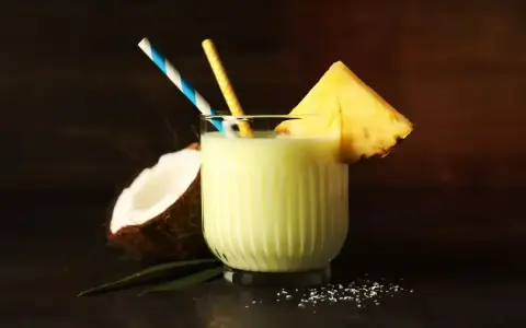 Orzeźwiający drink z mlekiem skondensowanym, ananasem i kokosem, ozdobiony słomkami. Idealny na tropikalne popołudnie.