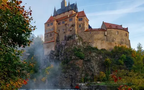 Zamek na skale nad wodospadem, jesienne liście i mgła tworzą malowniczy krajobraz. Wspaniałe wschodnie Niemcy atrakcje.