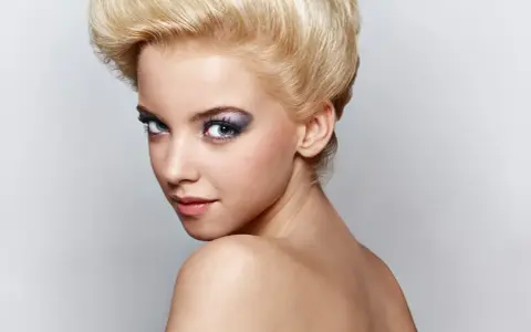 Mujer joven con peinado voluminoso y maquillaje llamativo, sus ojos de bambi cautivan la mirada.