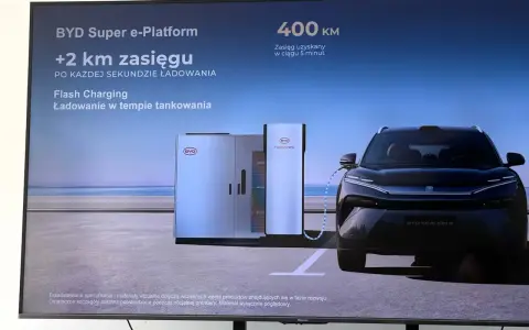 Czarny samochód elektryczny BYD Sealion 8 podłączony do stacji ładowania Flash Charging.