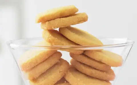 Stapel von goldbraunen Heidesand-Keksen in einer Glasbowle. Dieses Bild weckt Lust auf das beste Heidesand Rezept!