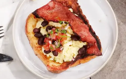 En tallrik med fattiga riddare toppad med äggröra, svarta bönor och salsa.