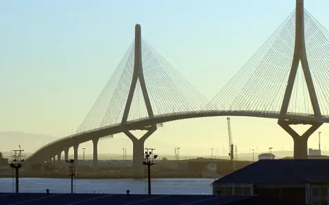 El imponente puente de Cádiz se alza sobre el agua, con sus cables tensos y pilares icónicos contra un cielo despejado.