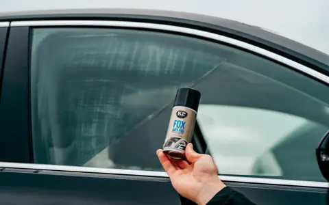 Dłoń trzyma puszkę preparatu K2 FOX ANTI-FOG, który zapobiega zaparowaniu szyb w aucie.