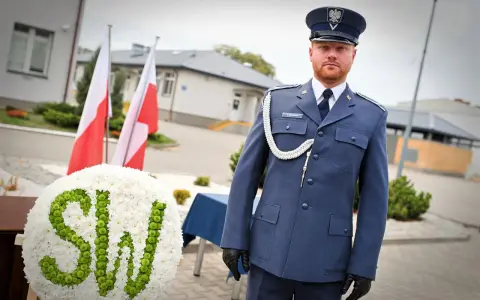 Mężczyzna w mundurze galowym SW, biało-zielony wieniec z napisem SW, polskie flagi.