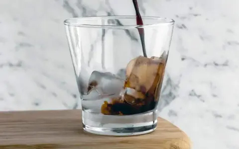 Kall kaffedrink hälls i ett glas med is.