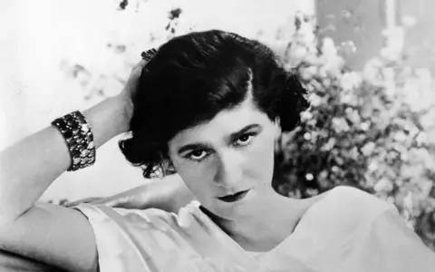 Coco Chanel negli anni '20, con un bracciale scintillante e un'espressione enigmatica.