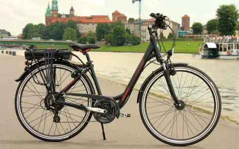 Rower z widocznym bagażnikiem i baterią, gotowy do konwersji na elektryczny. W tle zamek Królewski na Wawelu.