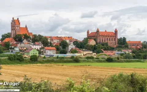 Widok na miasteczko z ceglanymi zamkami i kościołami, otoczone zielenią. W oddali pola uprawne. Wspaniałe **atrakcje** czekają na odkrycie!
