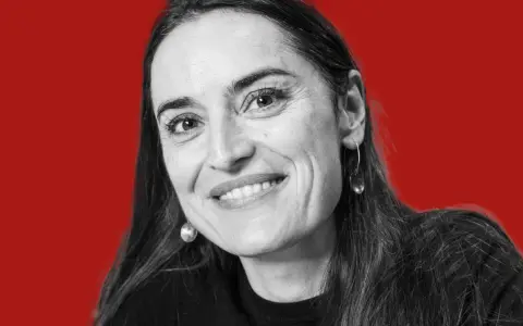 Uśmiechnięta kobieta z długimi włosami, w czarnej bluzce, z okrągłymi kolczykami. Mówi: "nie jestem twoim polakiem".