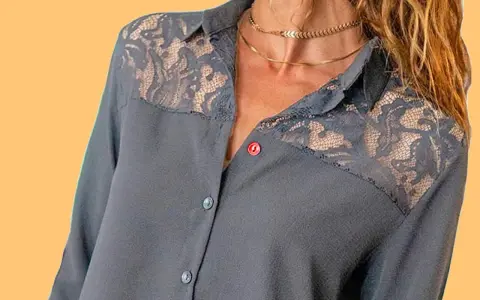 Chemise grise avec empiècements en dentelle sur les épaules. Le boutonnière fille est sur le côté gauche.