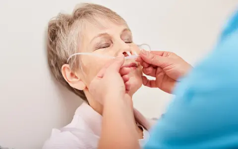 Ältere Frau mit Nasenbrille zur Sauerstofftherapie, ein Zeichen des COPD-Krankheitsbildes.