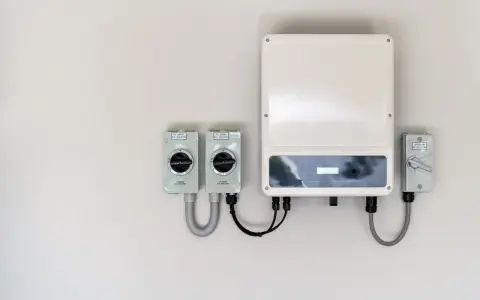 En vit vägg med en solcells-växelriktare och tre D.C. isolatorer. En del av systemet för att omvandla solenergi till el.
