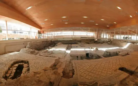 Resti archeologici della domus del chirurgo, con pavimenti a mosaico ben conservati sotto una moderna copertura in legno e vetro.
