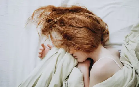 Ruda dziewczyna z burzą włosów, która może inspirować, jak wiazać wlosy na noc, by rano były gładkie.