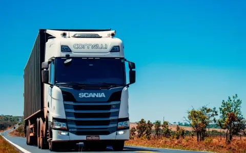 Camión Scania blanco en carretera soleada. Pensando en el coste del carnet de camión para conducir este gigante.