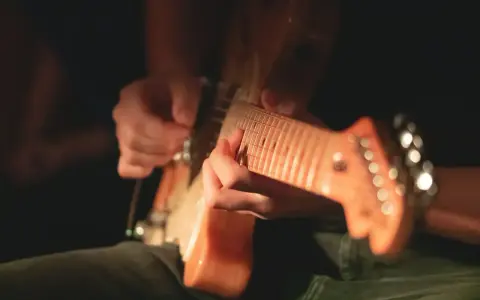Ręce grające na gitarze elektrycznej, idealne do nauki jak nauczyć się grać na gitarze elektrycznej.