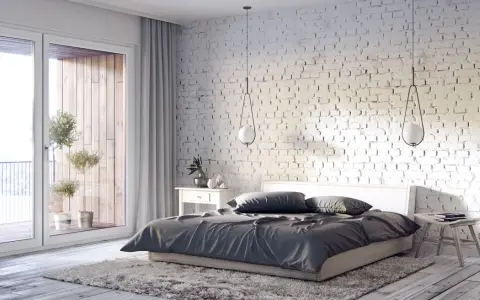 Przytulna sypialnia inspiracje: biała cegła, duże okno z widokiem na balkon, drewniana podłoga i miękki dywan tworzą relaksującą atmosferę.